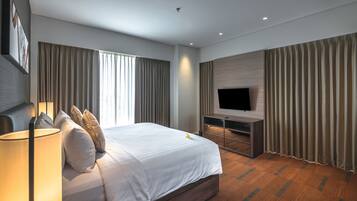 Una habitación de hotel moderna con una cama grande, un televisor de pantalla plana y piso de madera.