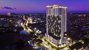 A high-rise hotel with multiple floors, surrounded by a cityscape at dusk.