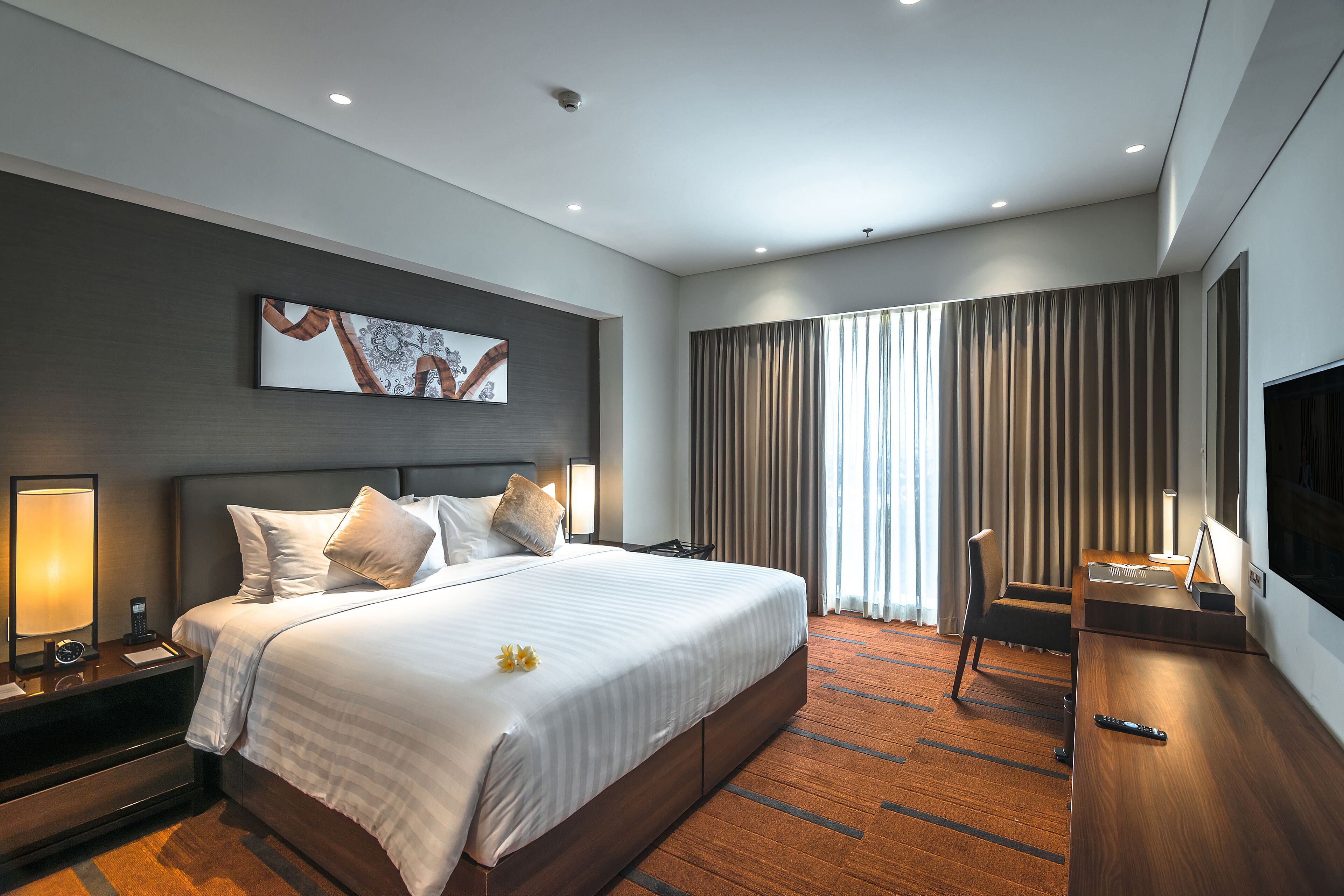 A modern hotel room with a large bed, a desk, and a TV.