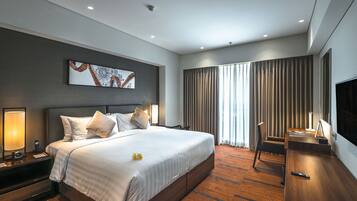 A modern hotel room with a large bed, a desk, and a TV.