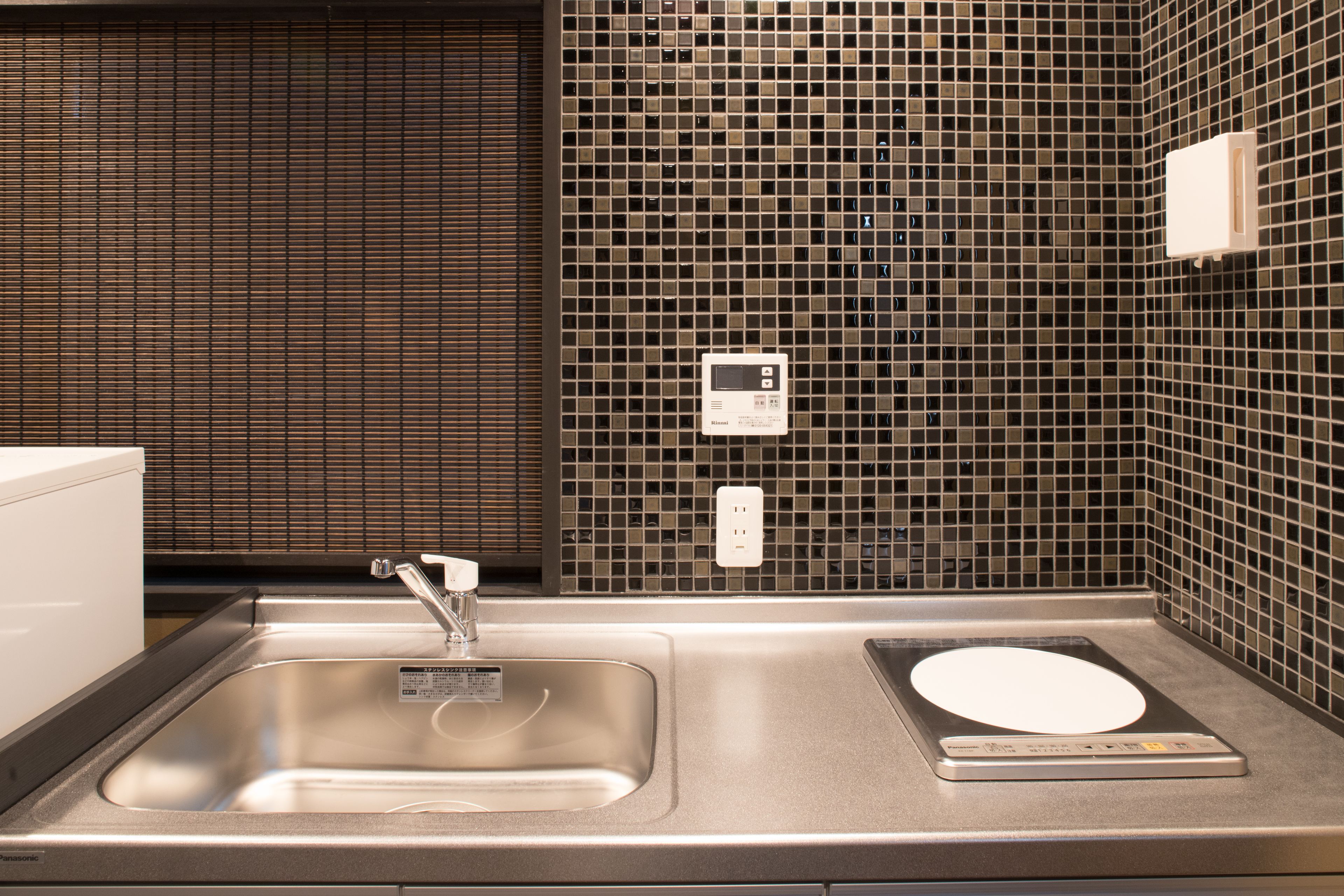 A modern kitchen with a stainless steel sink, a built-in oven, and a tiled backsplash.