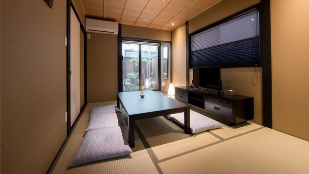 Perinteinen japanilaistyylinen huone, jossa on tatamimatto, matala pöytä, kaappi ja liukuovi, joka johtaa parvekkeelle.