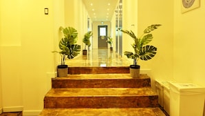 A well-lit hallway with marble steps, potted plants, and a door at the end. - OYO Rooftop Hostel (Seoul)