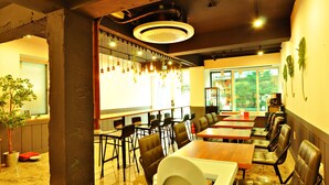 A restaurant with a long counter, booths, and hanging plants. - OYO Rooftop Hostel (Seoul)