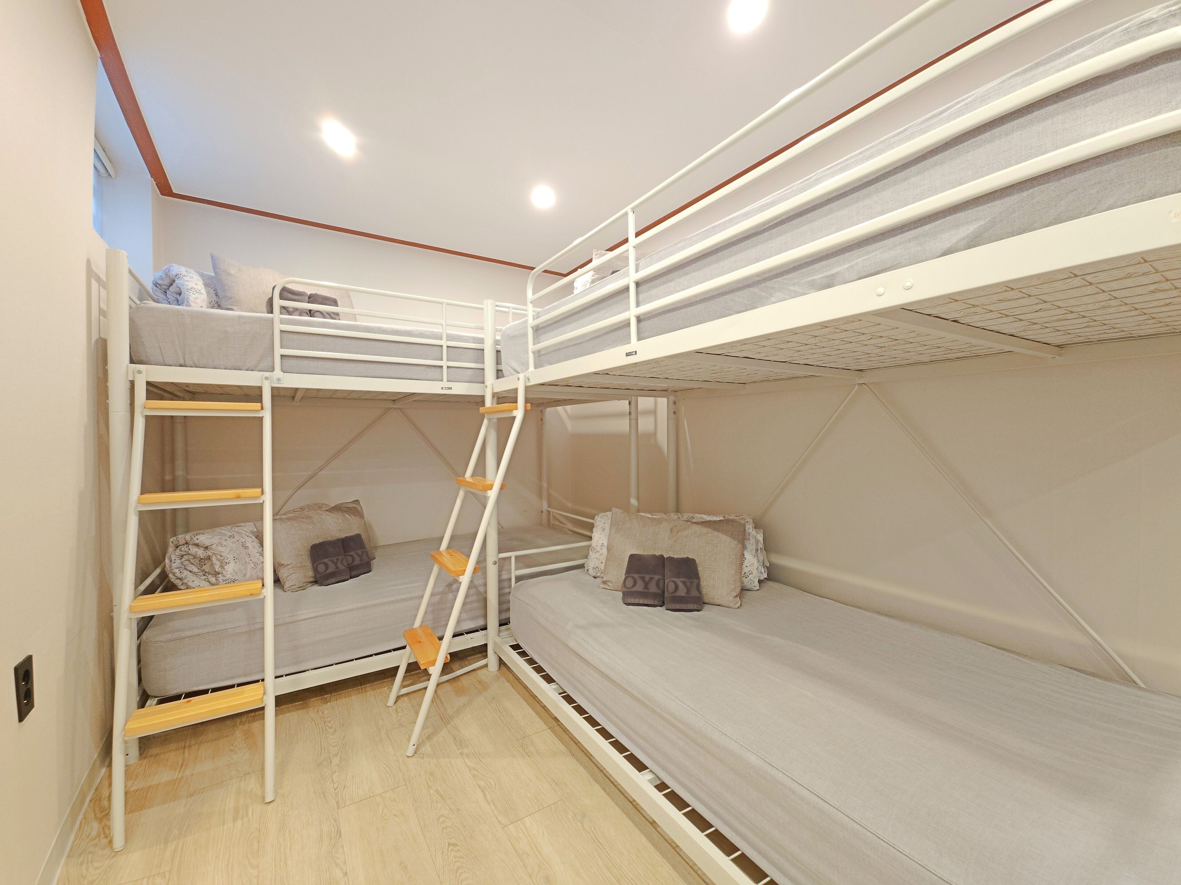 A bunk bed room with a ladder, pillows, and a light-colored floor.