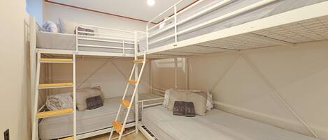A bunk bed room with a ladder, pillows, and a light-colored floor.