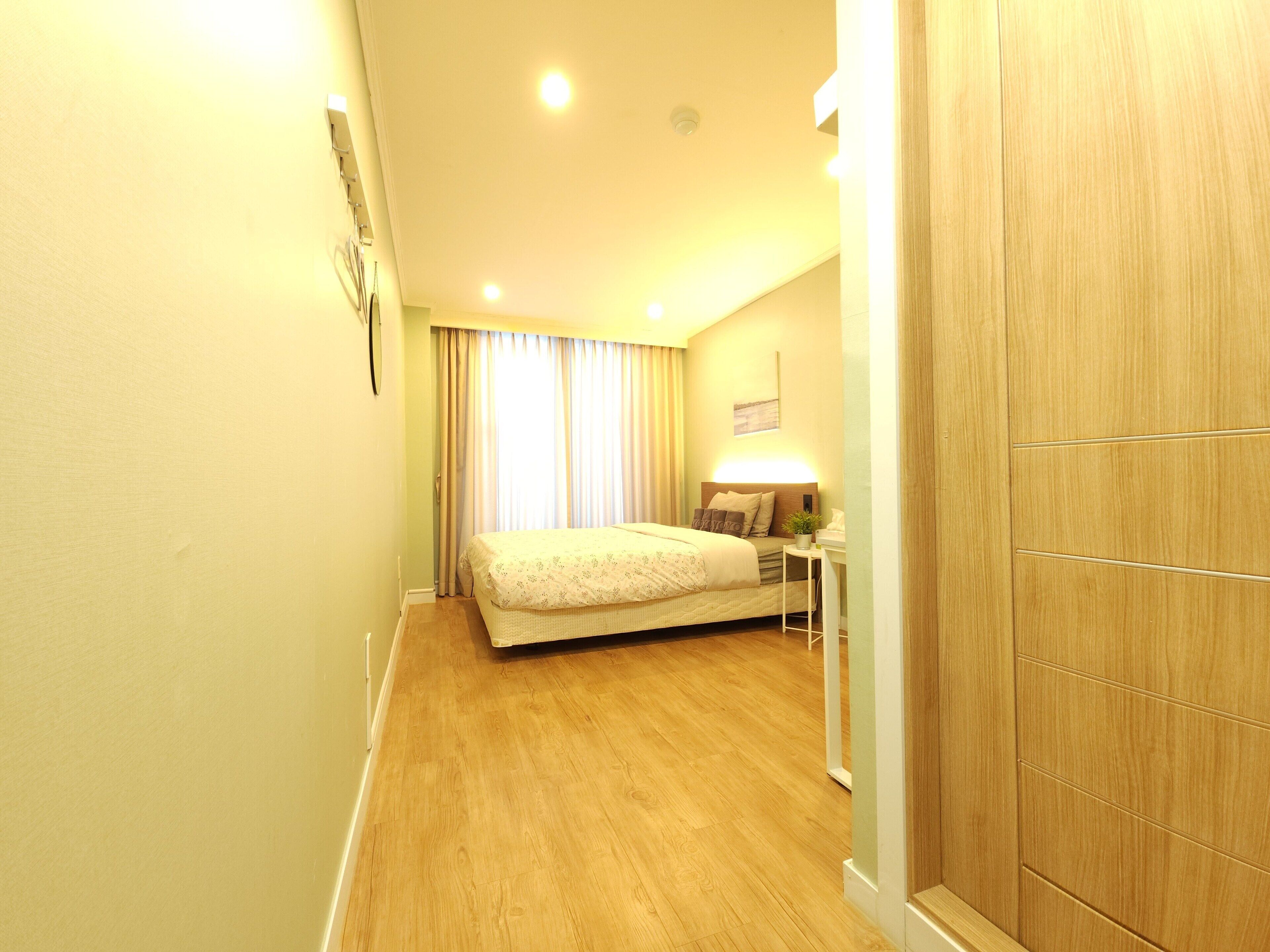 A hotel room with a bed, bedside table, lamp, and wooden wardrobe.
