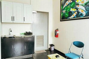 A kitchenette with a sink, cabinets, and a fire extinguisher. - Portal Residence (Jakarta)