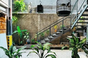 A staircase with metal railings, surrounded by potted plants, leading to a higher level. - Portal Residence (Jakarta)
