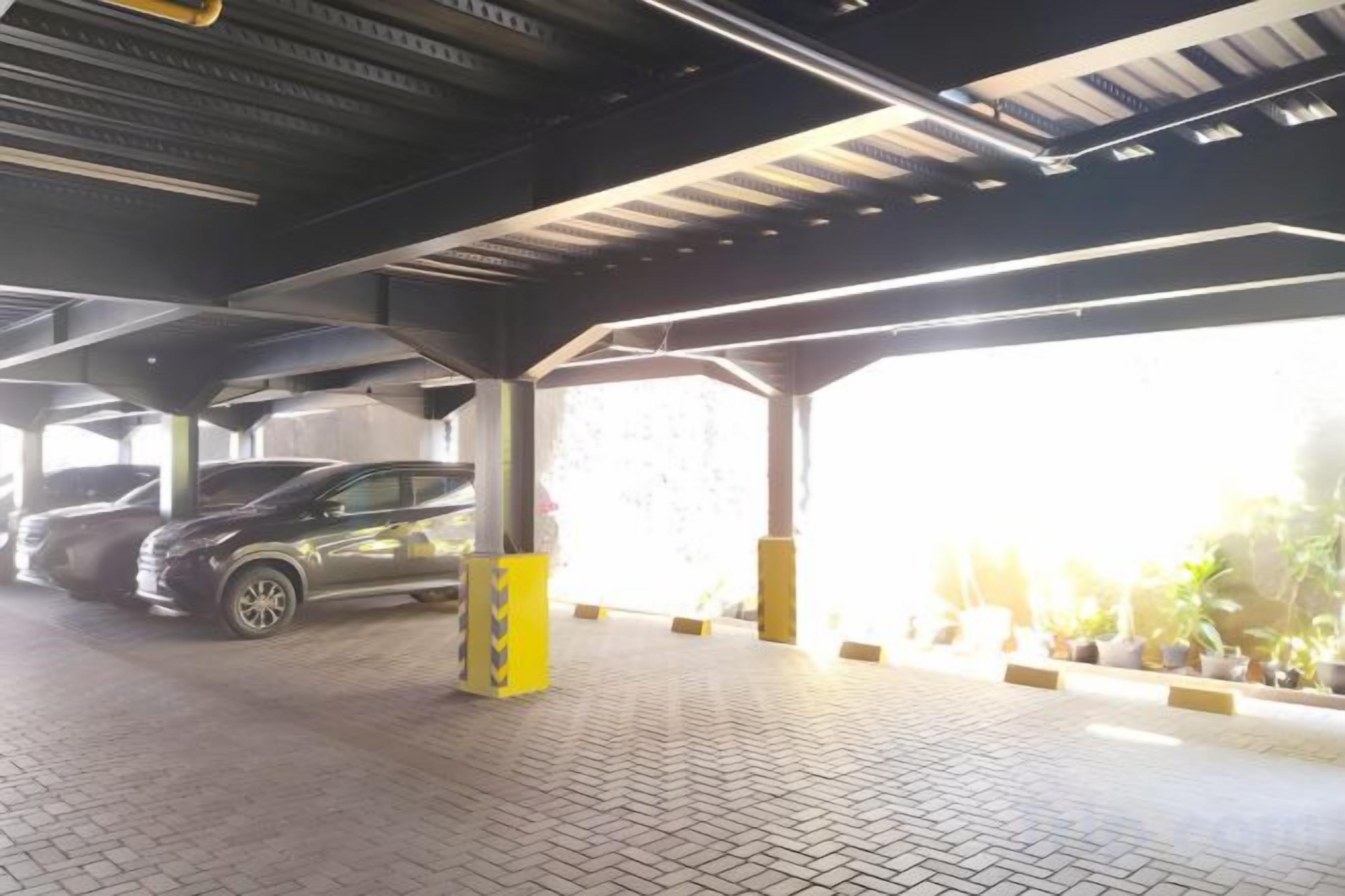 A covered parking area with a paved floor, a vehicle, and yellow bollards.
