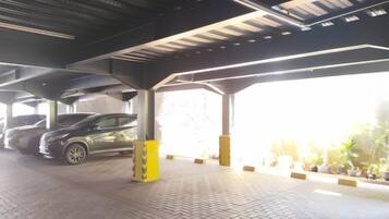 A covered parking area with a paved floor, a vehicle, and yellow bollards.