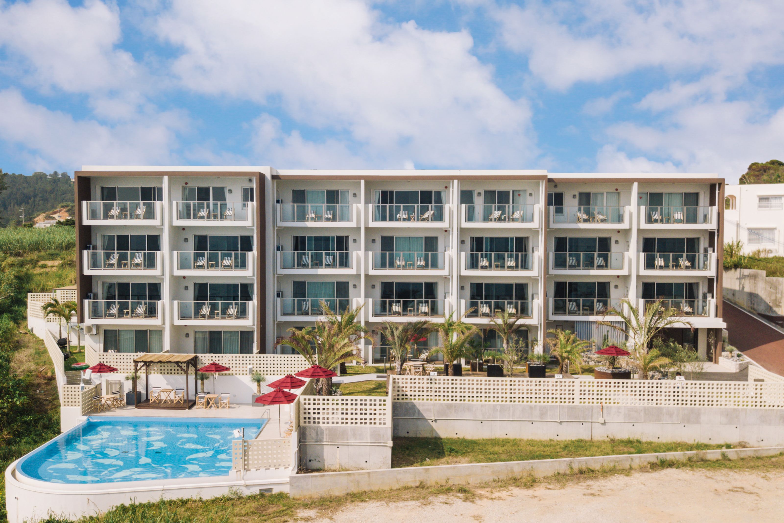 A multi-story hotel with a pool area, outdoor seating, and a view of the surrounding landscape.