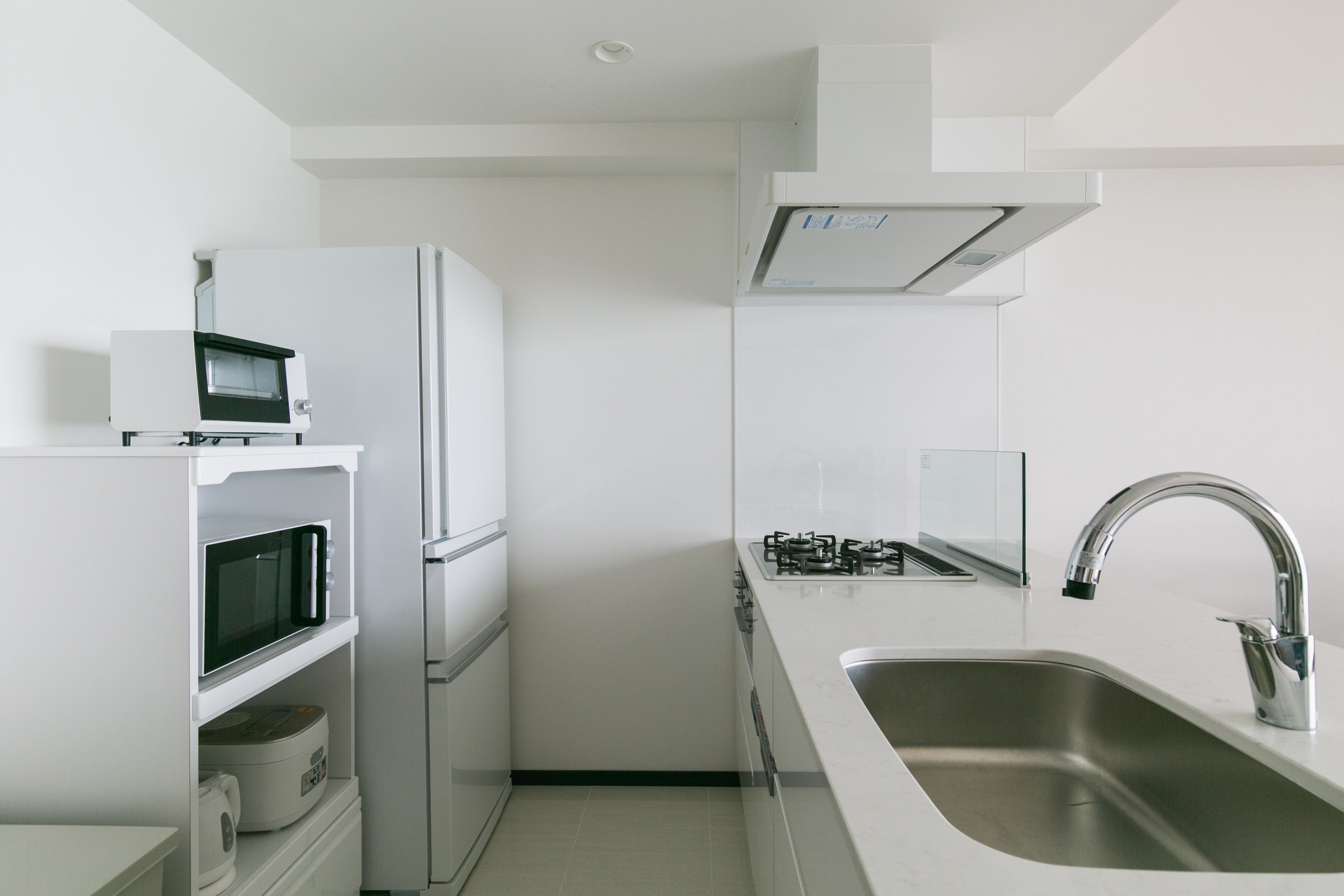 A modern kitchen with white cabinetry, a stainless steel sink, and a built-in microwave.
