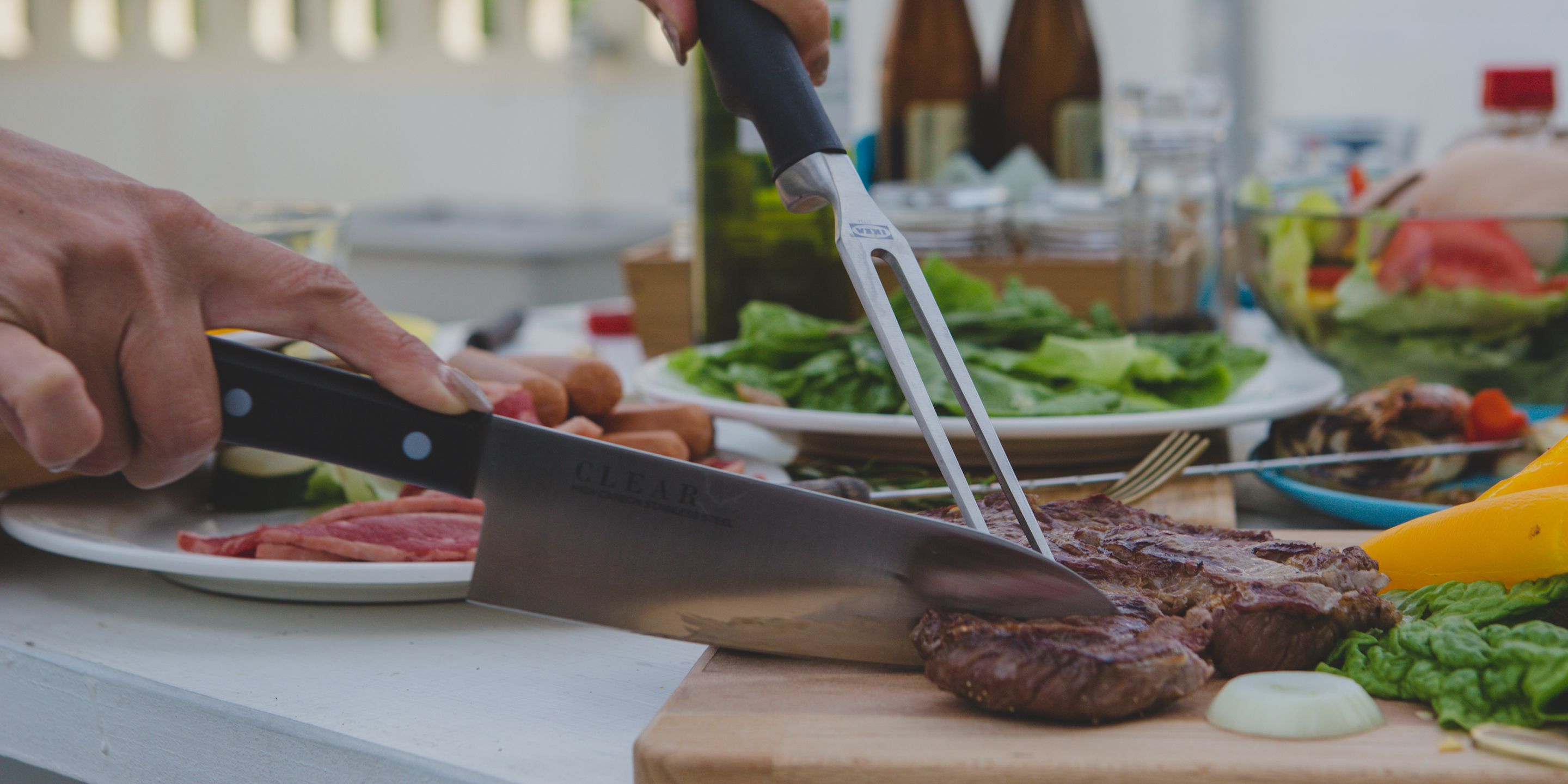 A person cutting a steak with a large cleaver on a wooden cutting board.