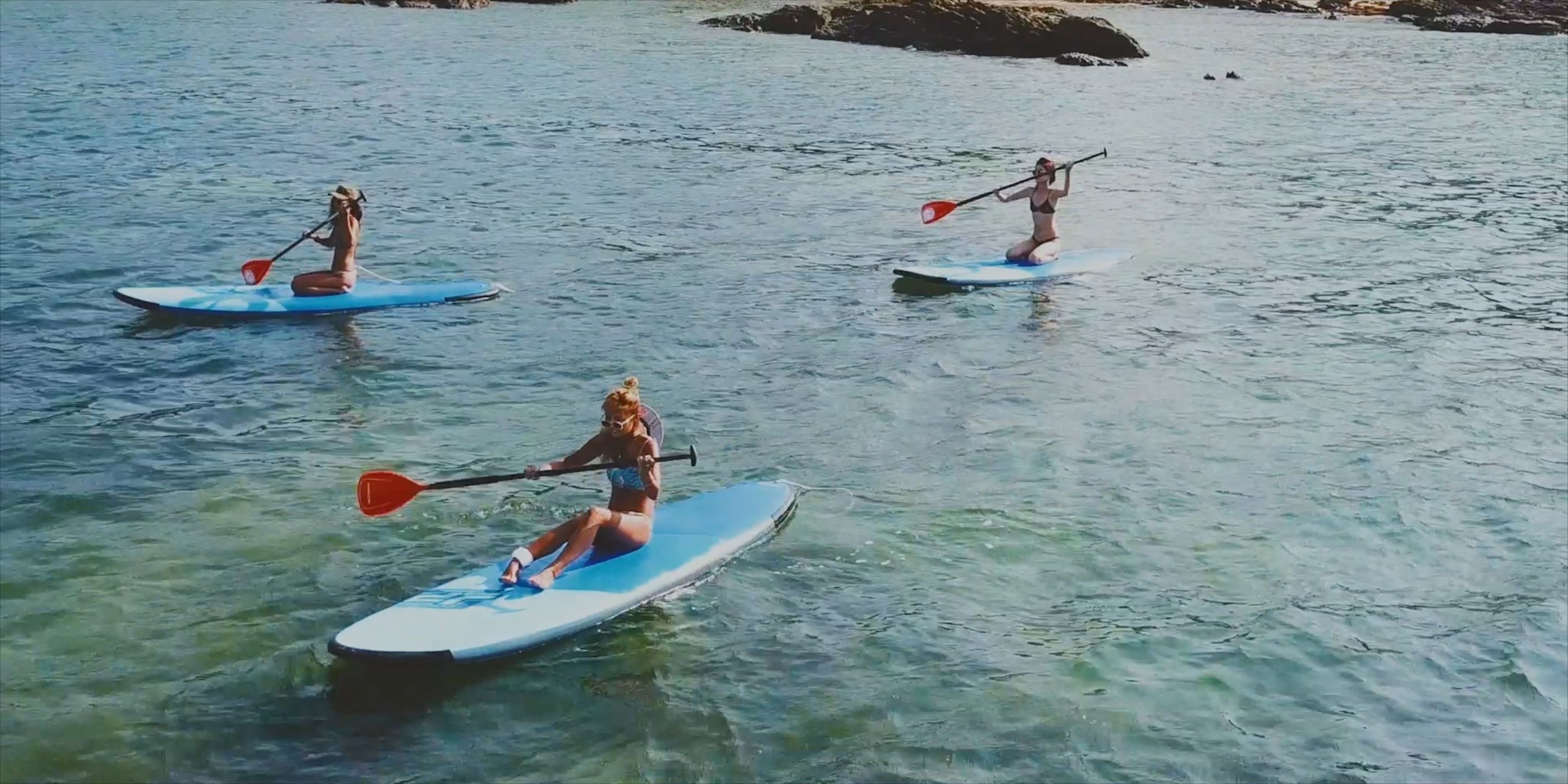 Tres personas haciendo paddleboard en aguas tranquilas.