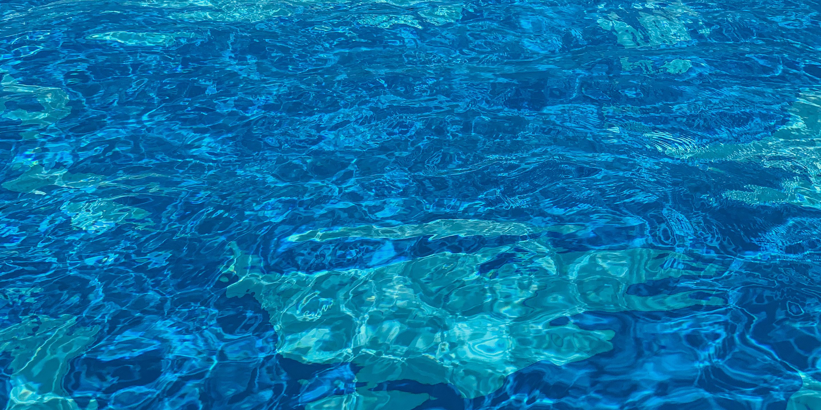 On voit clairement une piscine, avec des ondulations et des reflets visibles sur l’eau.