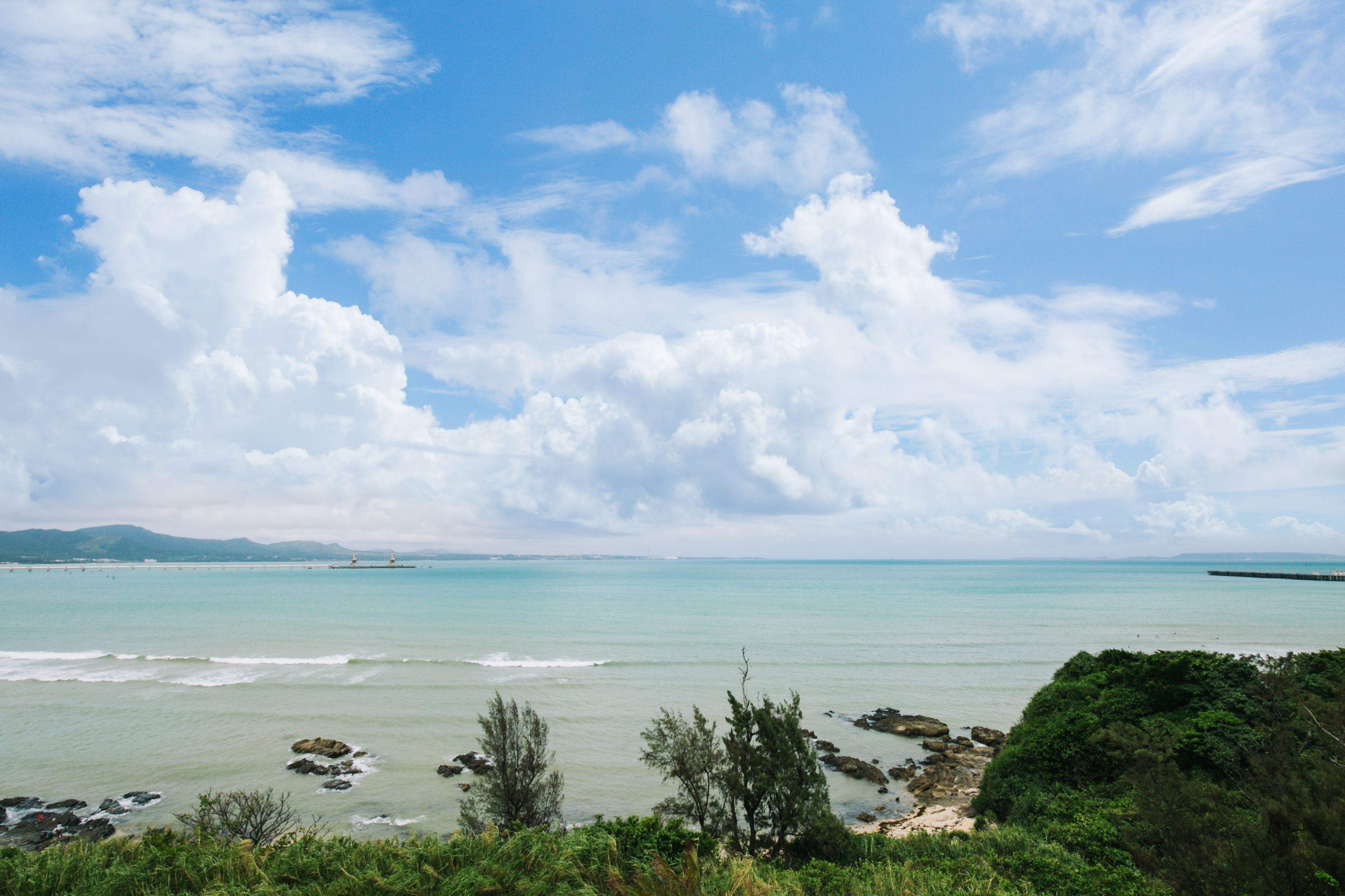 A coastal landscape with a lighthouse, clear sky, and turquoise sea.