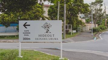 A directional sign for Hideout Okinawa Uruma, indicating a cafe, garden, and pool.