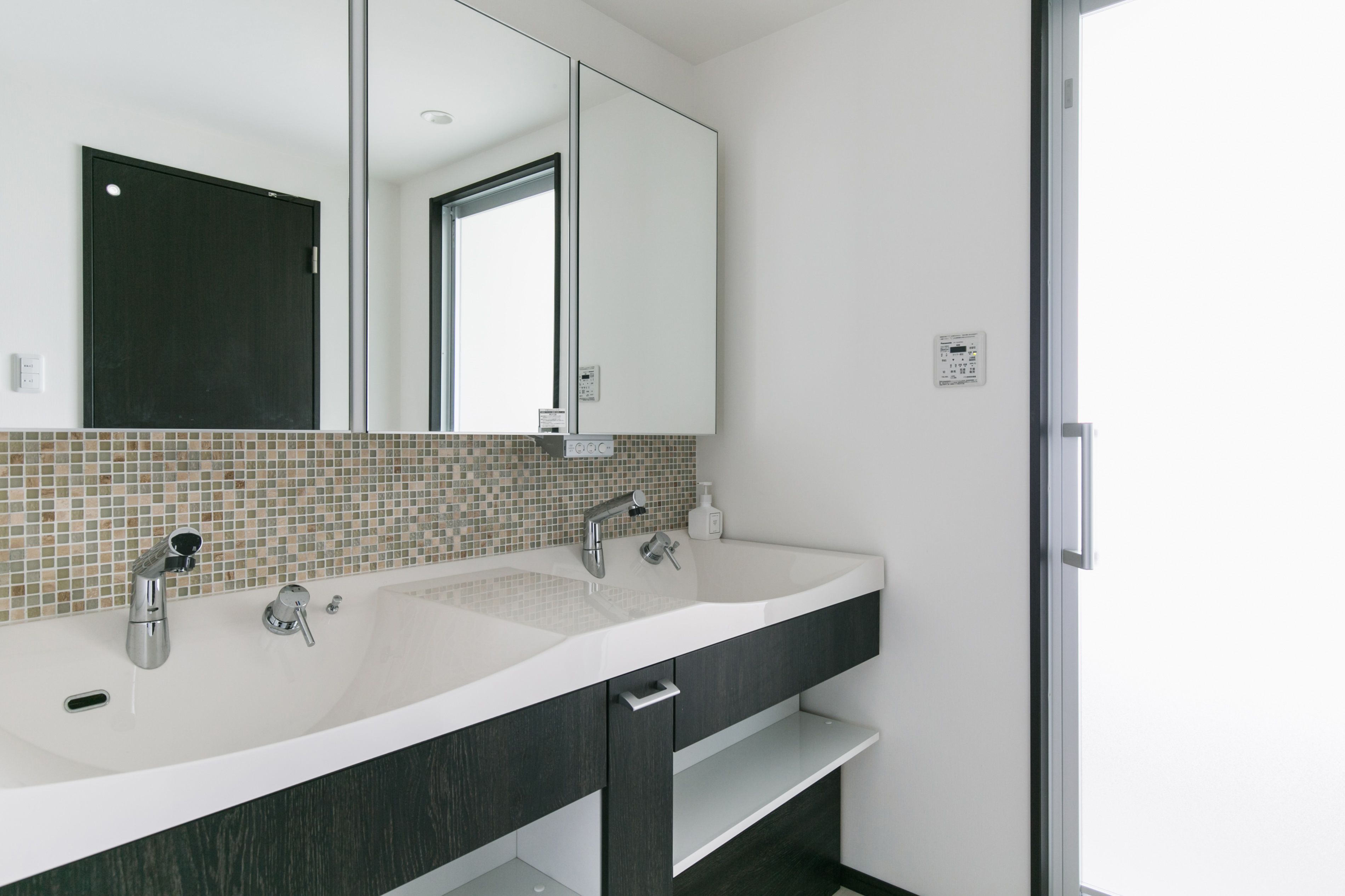 Un bagno moderno con uno specchio grande, due lavabi e uno schienale piastrellato.