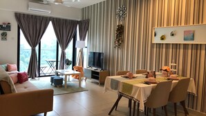 Un salon moderne comprenant un canapé, une table à manger pour quatre personnes, un téléviseur et une grande fenêtre avec des rideaux.