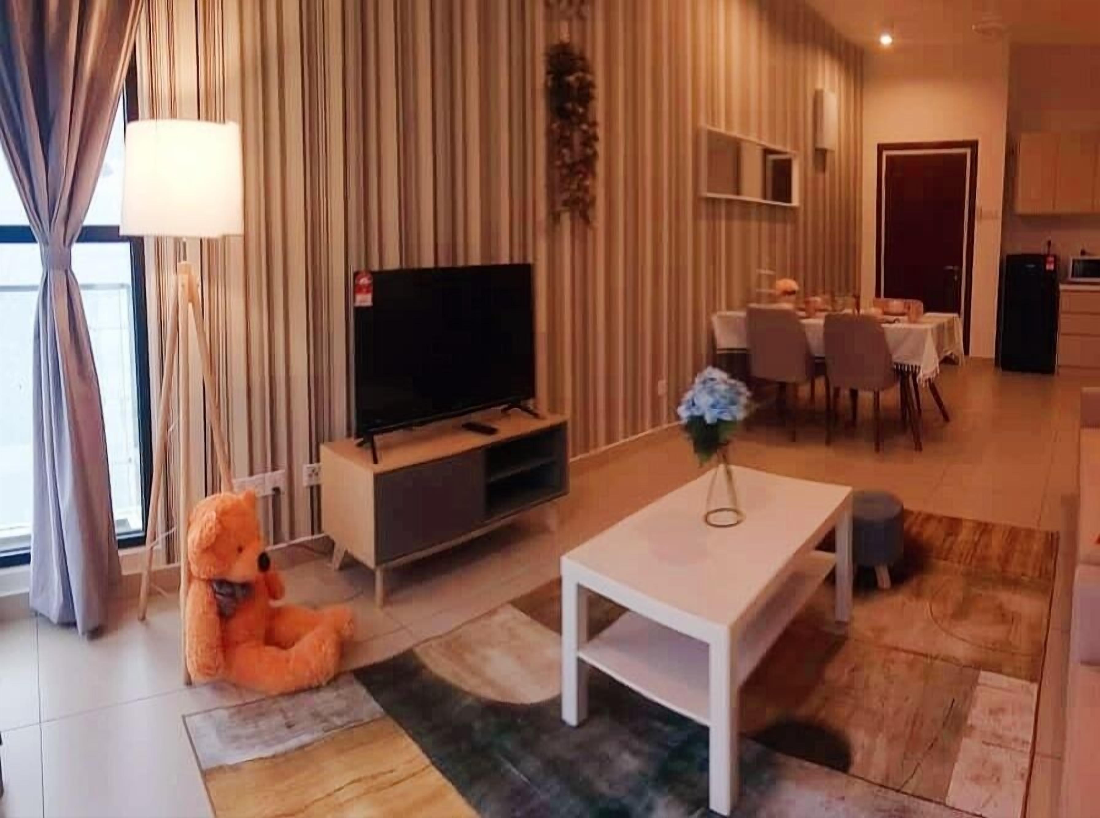 A modern living room with a flat-screen TV, a white coffee table, and a plush orange sofa.