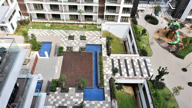 Un bâtiment moderne doté d’un jardin sur le toit, d’une piscine et d’une place dallée de motifs géométriques.
