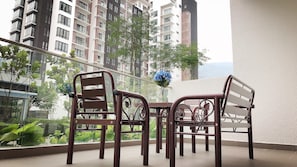 A balcony with a metal table and chairs, overlooking a residential area with high-rise buildings and greenery. - JW Midhill Genting Homestay (Genting Highlands)