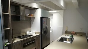 A modern kitchen with a built-in oven, a stainless steel refrigerator, and a small sink. - Apartment Santo Domingo, walled center  (Cartagena)
