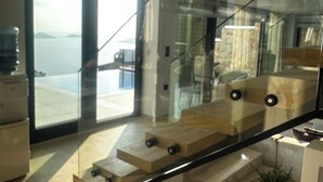 A modern interior with a glass staircase, a view of the sea, and a minimalist design.