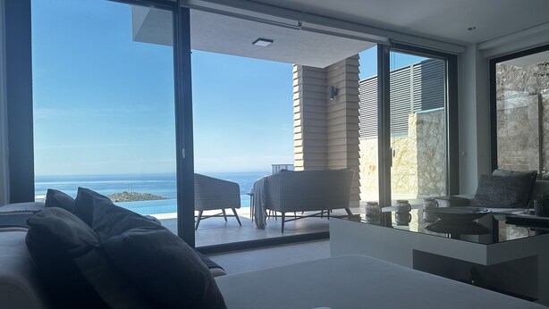 A modern room with a large sliding glass door leading to a balcony with a view of the ocean.