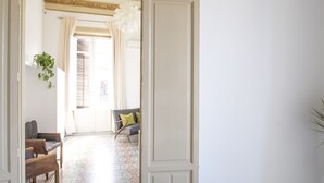 A dining area with a table set for two, a bowl of oranges on the table, and a view into a living room with a sofa and a plant. - Large bright apartment in Liberty building - Excellent position (Palermo)
