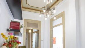 A hotel lobby with a wooden table, a vase of flowers, a chandelier, and a patterned floor. - Large bright apartment in Liberty building - Excellent position (Palermo)