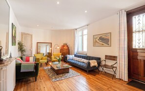 Uma sala de estar com sofá, cadeiras, uma mesa de centro e um radiador.