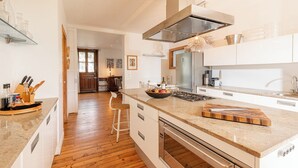 Een moderne keuken met een centraal eiland, roestvrijstalen apparatuur en houten vloeren.