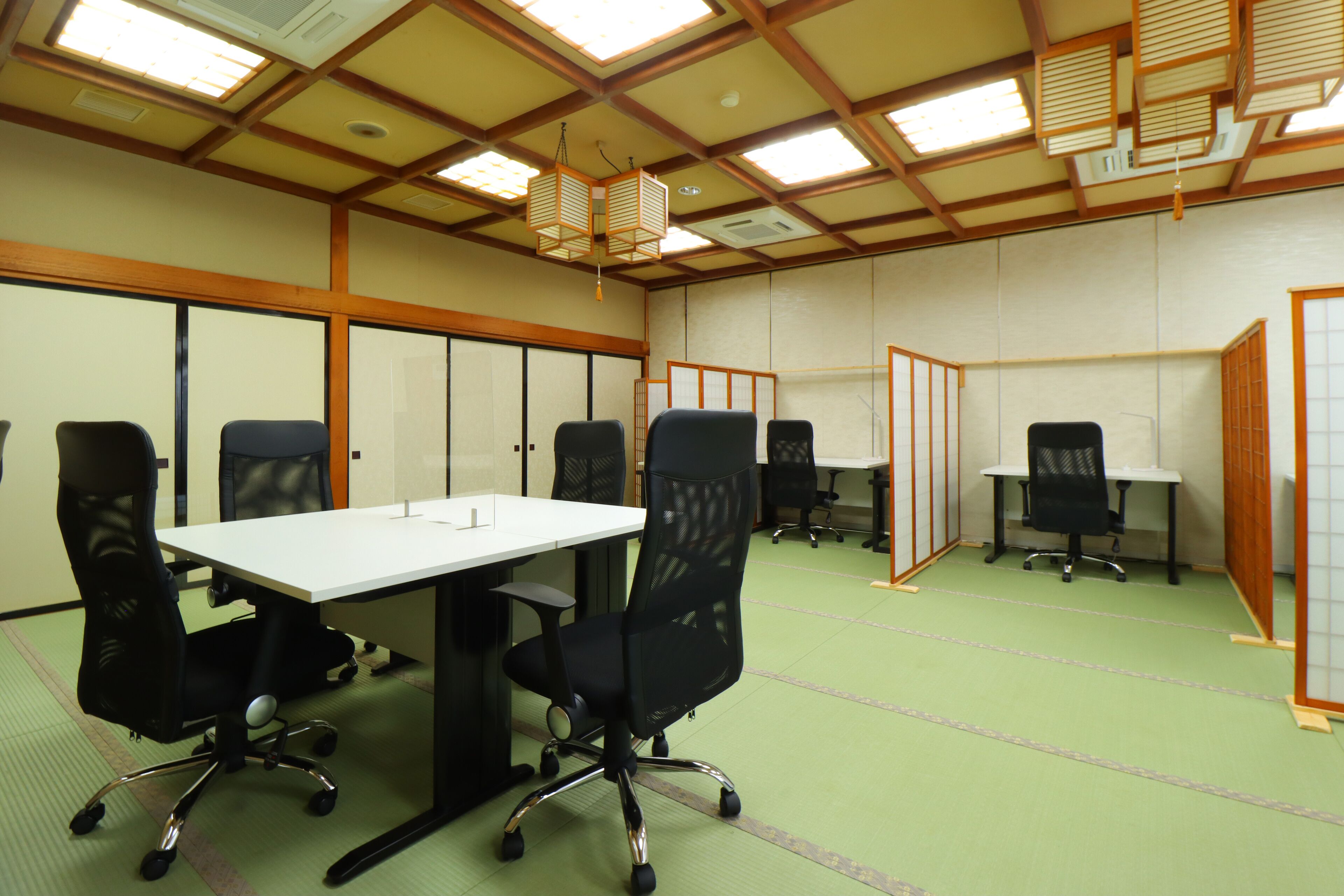 Un salón de conferencias con una larga mesa, varias sillas de oficina y un techo al estilo tradicional japonés.
