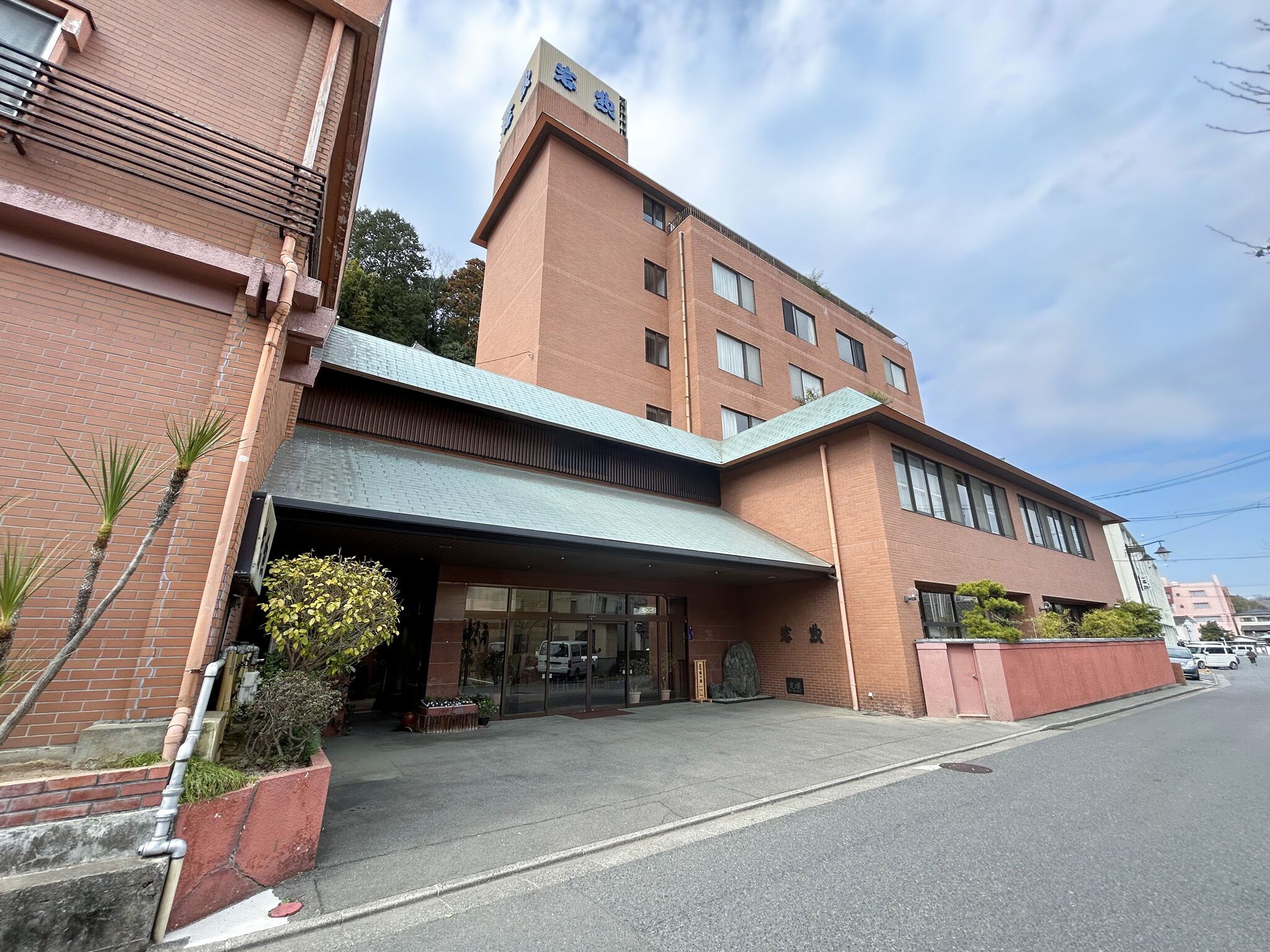 A multi-story hotel with a brick facade, a covered entrance, and a clear sky.