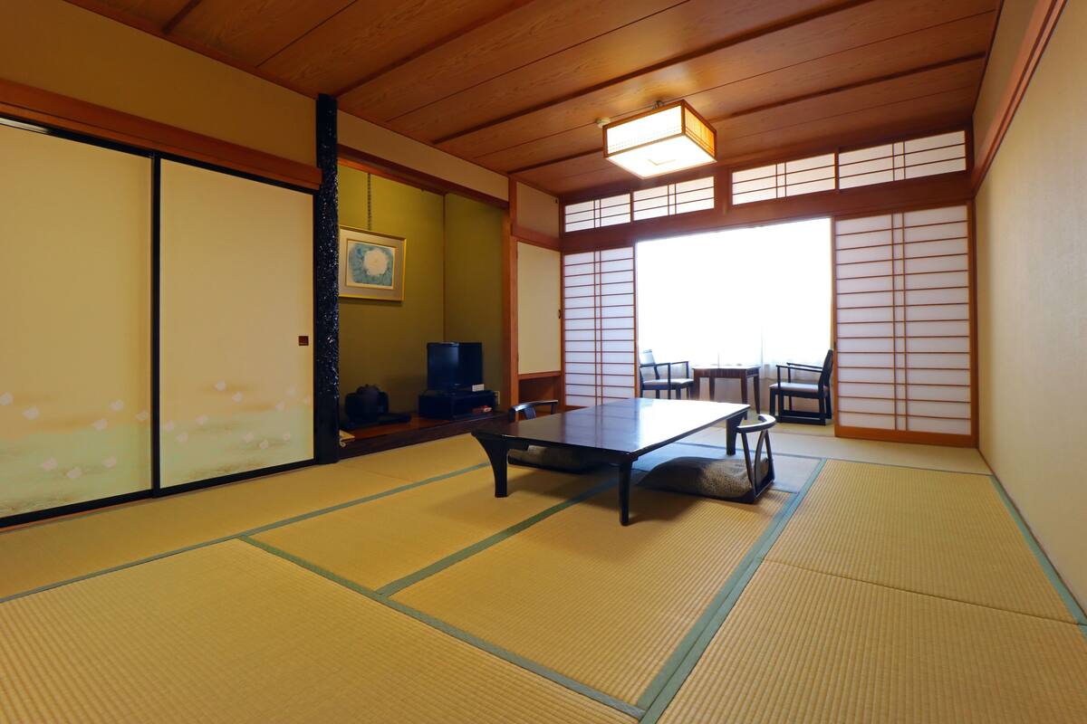 A tatami mat room with a low table, sliding doors, and a view through shoji screens.