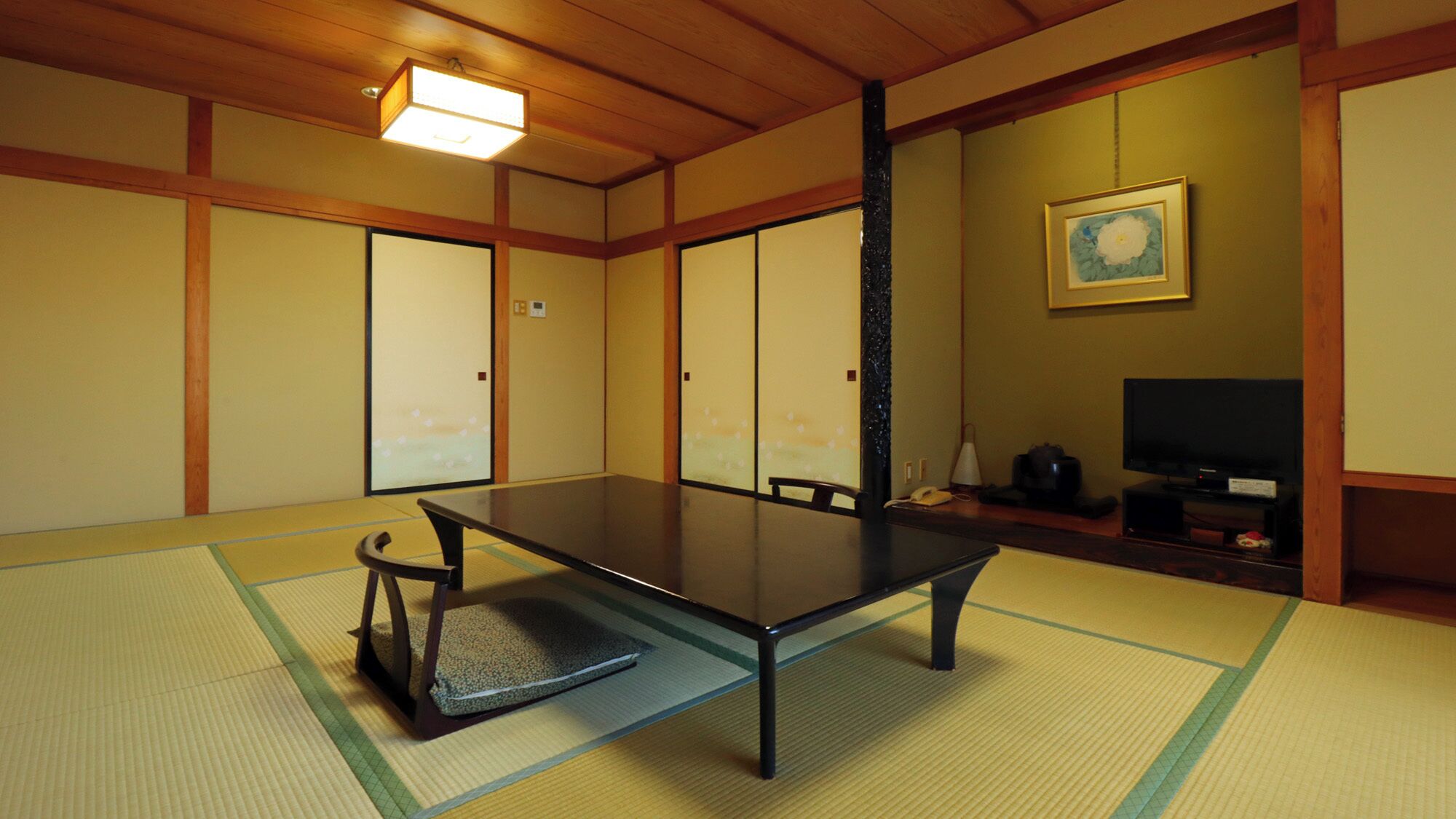 A traditional Japanese room with tatami flooring, a low table, and sliding doors.
