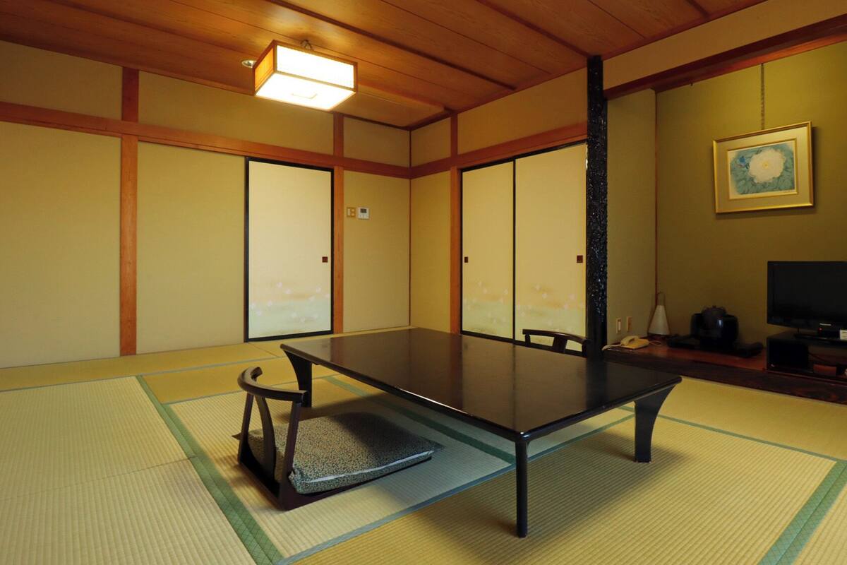 A traditional Japanese room with tatami flooring, a low table, and sliding doors.