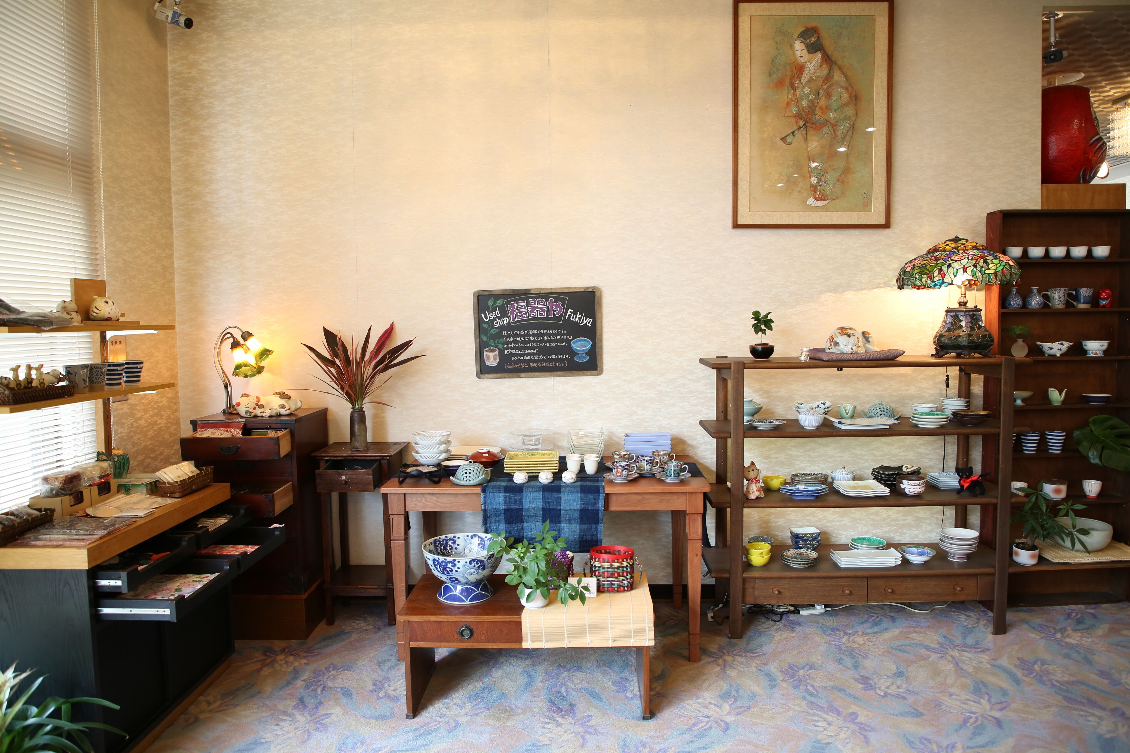 Una habitación japonesa tradicional con suelo de tatami, un juego de té y una estantería con cerámica.