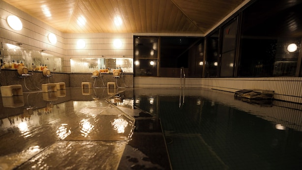 Une piscine intérieure moderne avec un plafond en bois, des murs carrelés et une paroi en verre.