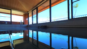 Une piscine à l’eau claire, de grandes fenêtres et un sol carrelé.