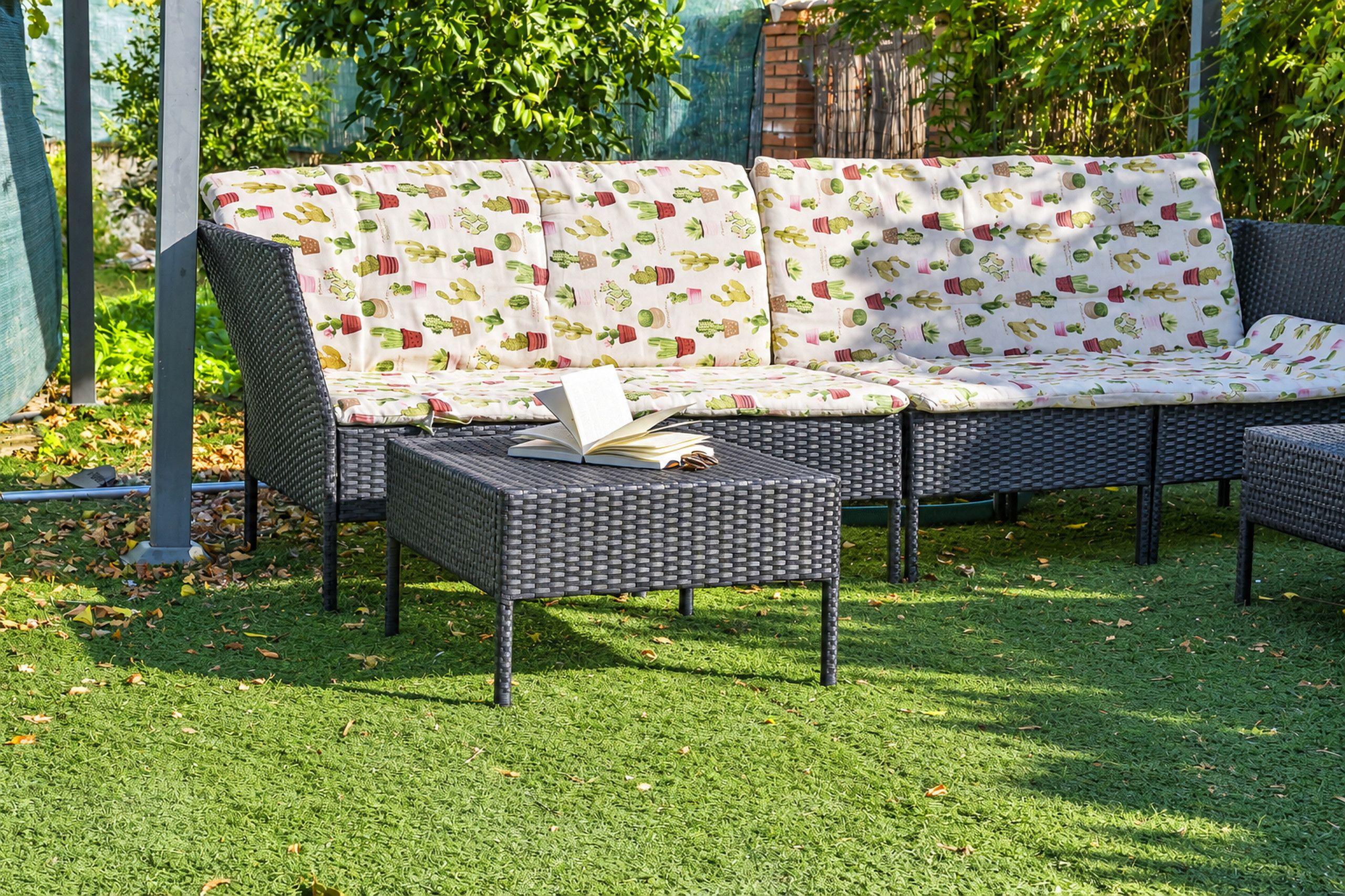 A garden seating area with a sofa and a table, surrounded by greenery.