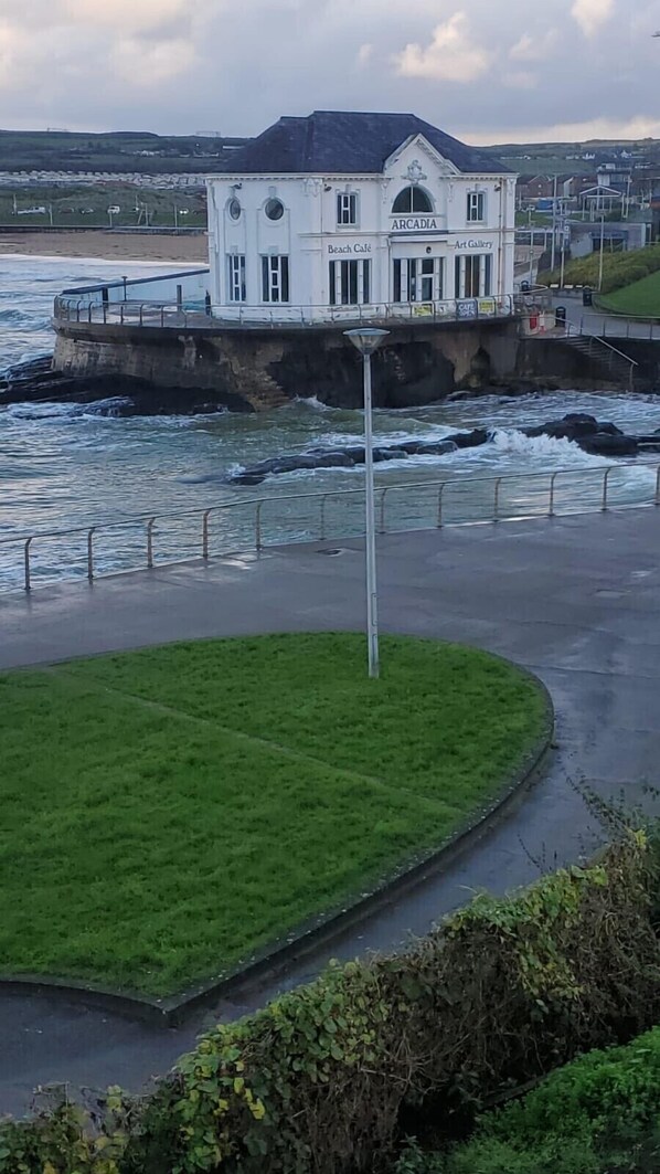 Un edificio costero con un letrero que dice "ARCADIA" y "Beach Café" en el piso superior.