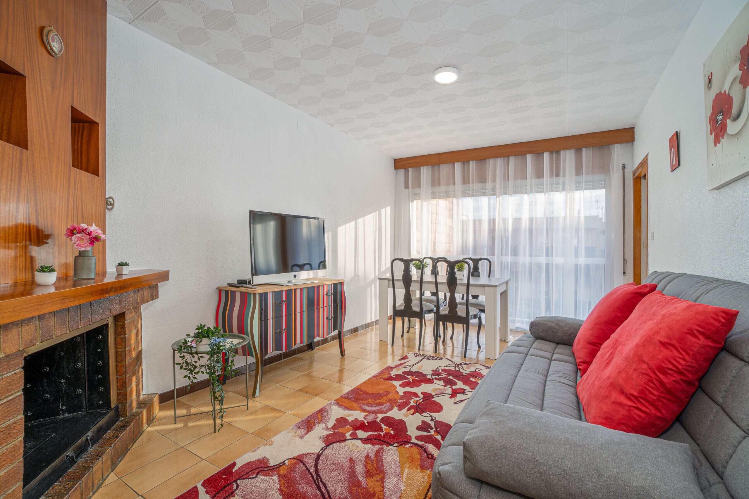 Ein Wohnzimmer mit Kamin, Sofa, Fernseher und Essbereich.