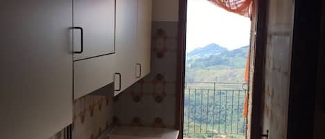 A kitchen with a large stove, cabinets, and a view of the outdoors through an open door.
