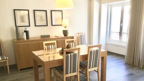 Un comedor con una mesa y sillas de madera, una lámpara y cuadros en la pared.