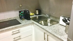 Una cocina con estufa, dos fregaderos, un tostador y una cafetera.