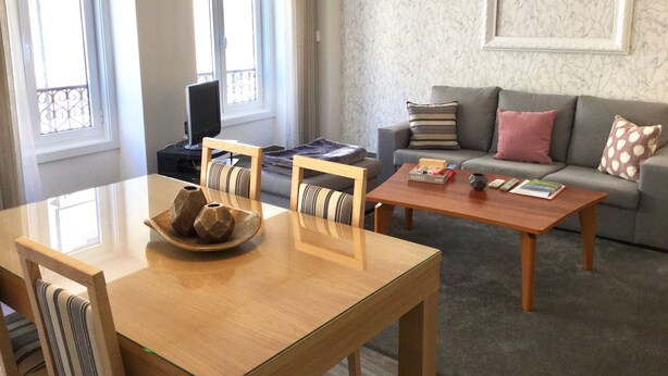 Una sala de estar con sofá, una mesa de centro, televisor y un comedor con sillas y una mesa.