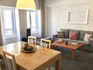 A living room with a sofa, a coffee table, a TV, and a dining area with chairs and a table. - Central & Charming Clérigos House 1 (Porto)